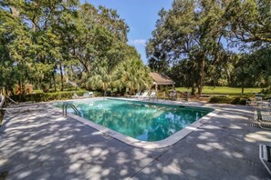 A swimming pool with lounge chairs and a gazebo surrounded by trees.