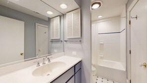 Un baño con lavamanos blanco, espejo y ducha.