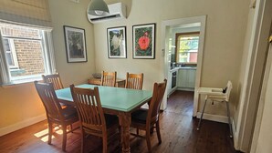 A dining area with a wooden table and chairs, a ceiling light, and framed pictures on the wall. - 3 bed 2 bath central cottage (Orange)