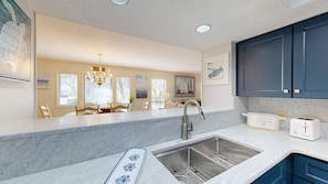 A modern kitchen with a built-in sink, a chandelier, and a dining area with a table and chairs.
