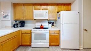 Fully equipped kitchen with a stove, microwave, refrigerator, and coffee maker.