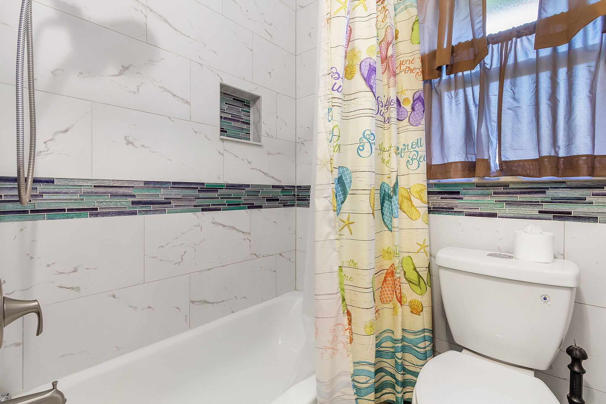 Een badkamer met een bad, toilet en douchegordijn.