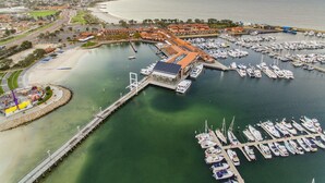 An aerial view of a marina with boats docked, a pier, and a beach area.