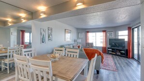 A spacious living area with a dining table, chairs, a sofa, and a television. - CRC 1206 - Newly Updated Condo with Ocean and Pool View (St Augustine)