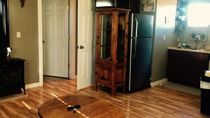 A kitchen with a refrigerator, a wooden cabinet, and a television on a stand.