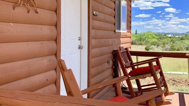 A wooden cabin with a porch, a door, and a sun decoration.