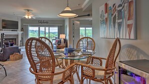 Un espace repas avec des chaises en osier, une table en verre et des luminaires suspendus.