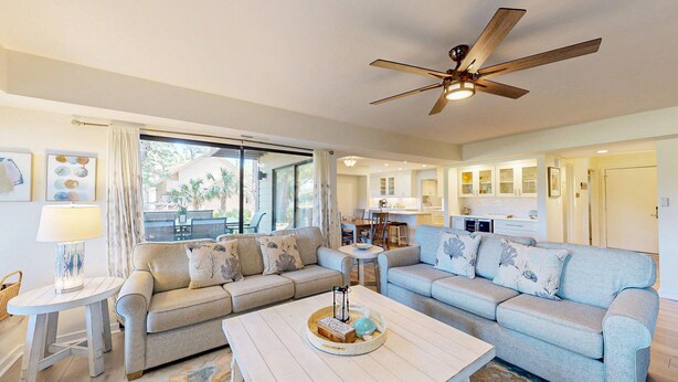 A spacious living room with a large sofa, a coffee table, and a ceiling fan. - Many Updates in this Large Four Bedroom Villa with Golf Views! (Hilton Head)