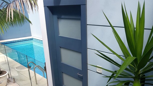 Um edifício moderno com porta de vidro que dá para uma área de piscina.