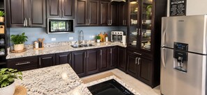 A modern kitchen with dark cabinetry, stainless steel appliances, and a granite countertop. - Glass House Arenal Private Pool + Volcano Views (La Fortuna)