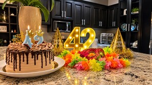 A kitchen with a birthday cake, candles, and decorations. - Glass House Arenal Private Pool + Volcano Views (La Fortuna)