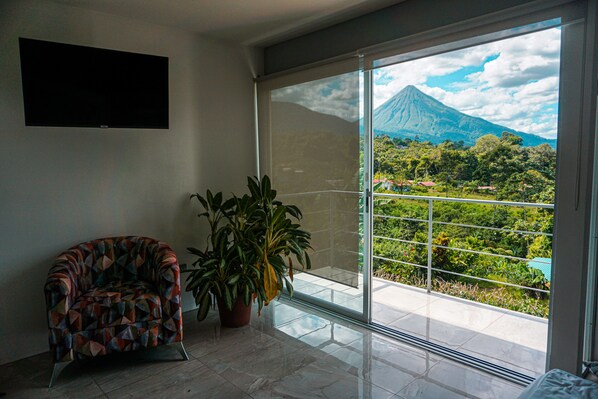 A room with a large sliding glass door leading to a balcony with a view of a mountain. - Glass House Arenal Private Pool + Volcano Views (La Fortuna)