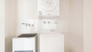 Une petite buanderie équipée d’un lave-linge à chargement frontal et d’un appareil combiné lave-linge et sèche-linge.