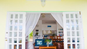 An open doorway leading to a room with a ceiling fan, a bookshelf, and a blue sofa with a floral cushion.