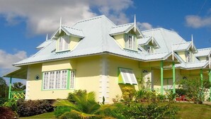 A multi-story building with a yellow facade and green accents, featuring a prominent central tower and multiple windows.