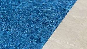 Ein Schwimmbecken mit klarem, blauem Wasser und einer gefliesten Liegefläche.