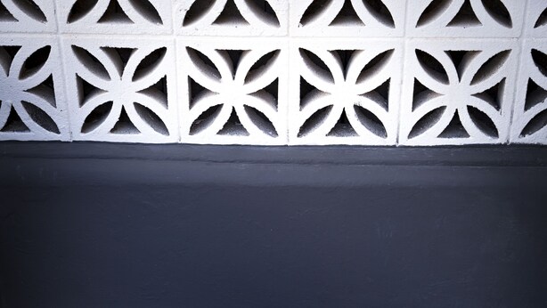 A small round table with a vase of purple flowers, two black chairs, and a decorative white wall with geometric patterns. - Vacational Housing CAÑAMO, Feel the Quiet Difference .... (Tamaduste)