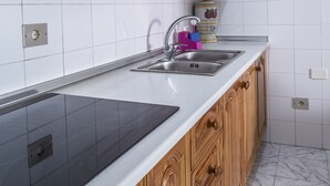 A kitchen with wooden cabinets, a stainless steel sink, and a black induction cooktop. - Vacational Housing CAÑAMO, Feel the Quiet Difference .... (Tamaduste)