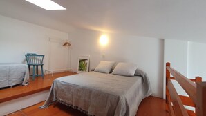 A bedroom with a bed, a chair, a wardrobe, and a bedside table.
