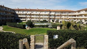 A multi-story hotel with balconies, a swimming pool, and well-maintained gardens.