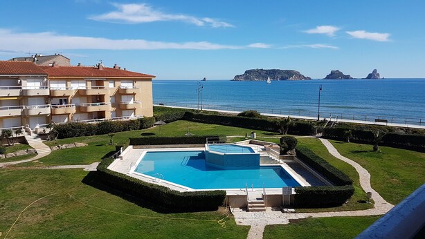 A pool area with a view of the sea and a building with balconies.