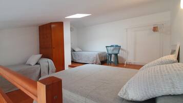 A bedroom with two beds, a wooden wardrobe, a chair, and a wardrobe with a mirror.