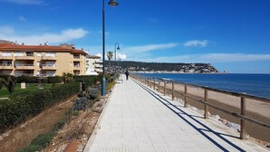 A coastal promenade with a paved walkway, a wooden railing, and a view of the sea.