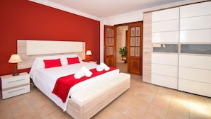 Een slaapkamer met een groot bed, rode muren, een houten garderobe en een nachtkastje met een lamp.