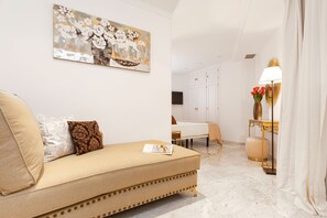 A modern living room with a sofa, a dining area, and a painting on the wall.