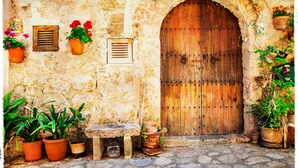 A rustic stone wall with a wooden door, potted plants, and a bench. - Can Xim 080 fantastic house close to the beach, with terrace, garden, barbecue and WiFi. (Alcúdia)