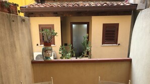 A small outdoor patio with a white table and two chairs, a bowl of fruit, and a tiled floor. - Apartment in Taormina center (Taormina)