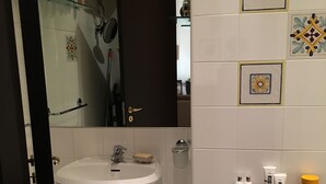 A bathroom with a white sink, a mirror, and a wooden cabinet. - Apartment in Taormina center (Taormina)