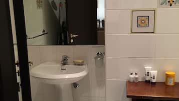 Un bagno con un lavandino bianco, uno specchio e un armadietto in legno.