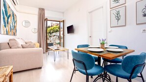 Ein modernes Wohnzimmer mit einer Couch, einem Esstisch mit Stühlen und Kunstwerken an den Wänden.