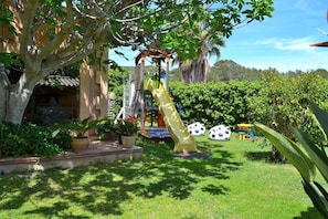 Enjoy a serene and natural atmosphere in our lush garden, featuring a yellow slide and beautifully trimmed hedges.