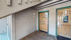 Eine Holzbalkonveranda mit der Nummer 561 über einer Tür, einem Buntglasfenster und einem türgrünen Türrahmen.