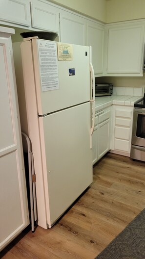 A kitchen with white cabinets, a white refrigerator, a microwave, and a stainless steel oven. - Snowcreek Resort Vacation Rental 561 (Mammoth Lakes)
