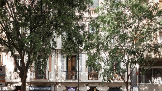Un edificio con varias fachadas comerciales, incluyendo una tienda Vespa Borrell y una tienda Maillon.