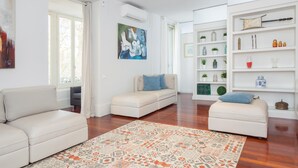 A modern living room with a beige sofa, a patterned rug, and a bookshelf filled with decorative items. - ART HOUSE CITY CENTRE UNIVERSITAT (BARCELONA)