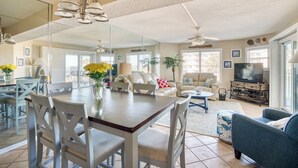 A spacious living area with a dining table, chairs, a sofa, and a television. - CRC 1205 - Beach Getaway for the Whole Family! Ocean View Condo (Saint Augustine)