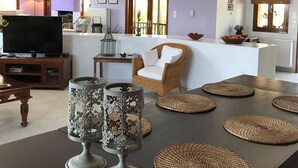 Uma sala de estar com televisão, um sofá e um espaço de jantar com jogos americanos.
