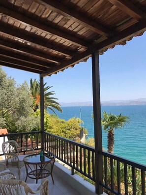 A covered outdoor area with a view of the sea, featuring a table and chairs.