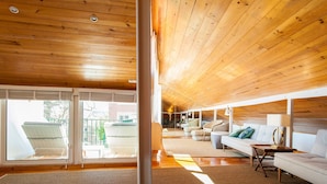 A spacious living area with a wooden ceiling, large windows, and a sofa set. - Santos River View Terrace - Boutique Duplex (Lisboa)