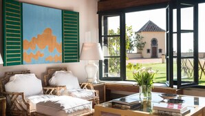 Una habitación acogedora con un sofá de mimbre, una mesa de centro de vidrio y vistas a un edificio a través de amplios ventanales.
