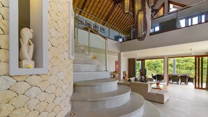A modern interior with a stone wall, a staircase, and a dining area with outdoor views.