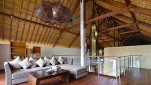 A spacious living area with a high ceiling, a large woven light fixture, a sofa set, and a wooden coffee table.