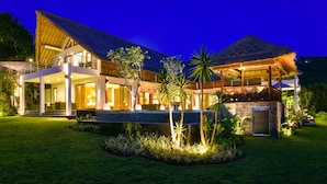A modern two-story house with a large balcony, a swimming pool, and a well-maintained garden.