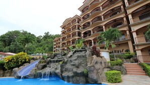 Ein Hotel mit Pool, Wasserfall und einem mehrstöckigen Gebäude mit Balkonen.