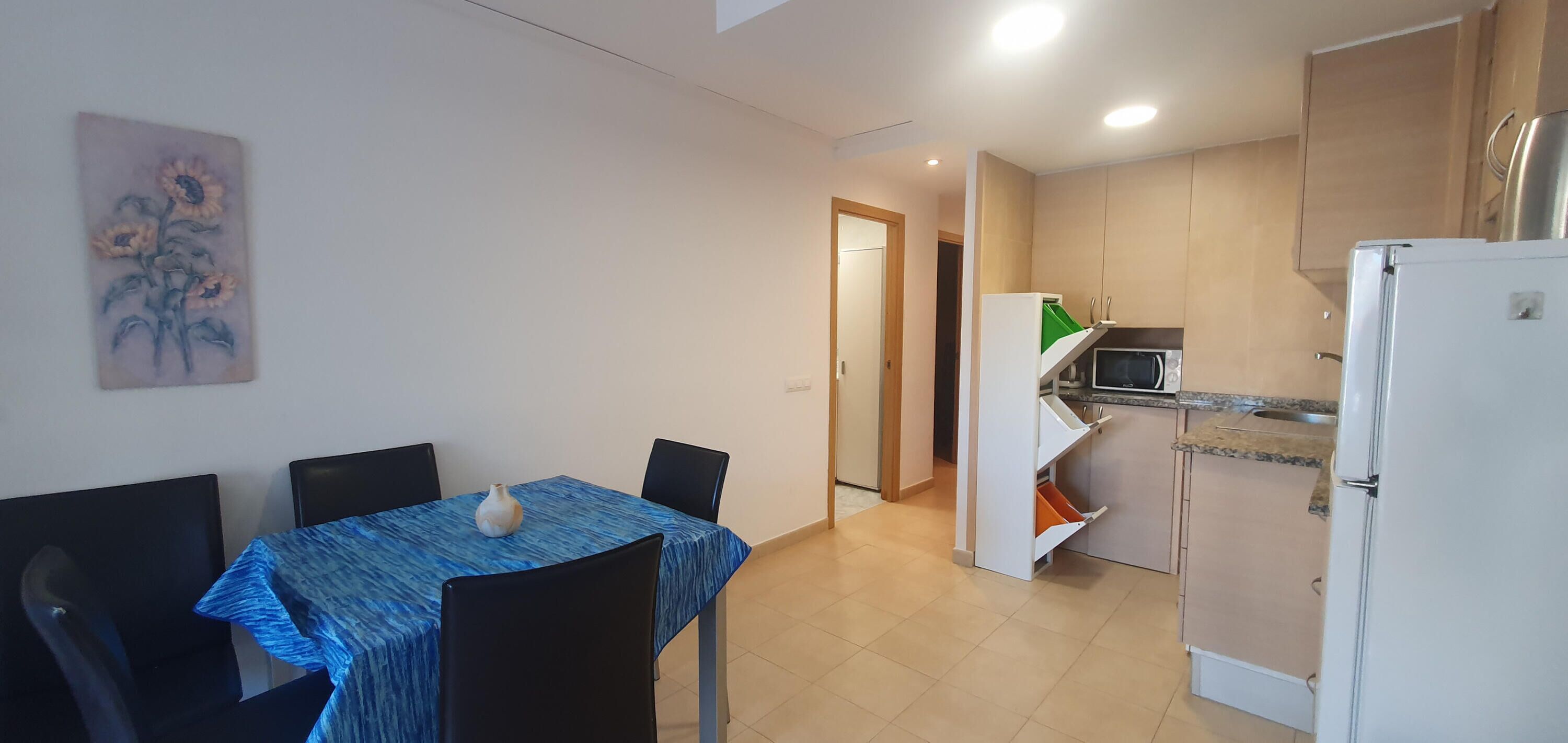 A compact kitchen with a microwave, refrigerator, and a small dining area with a table and chairs.