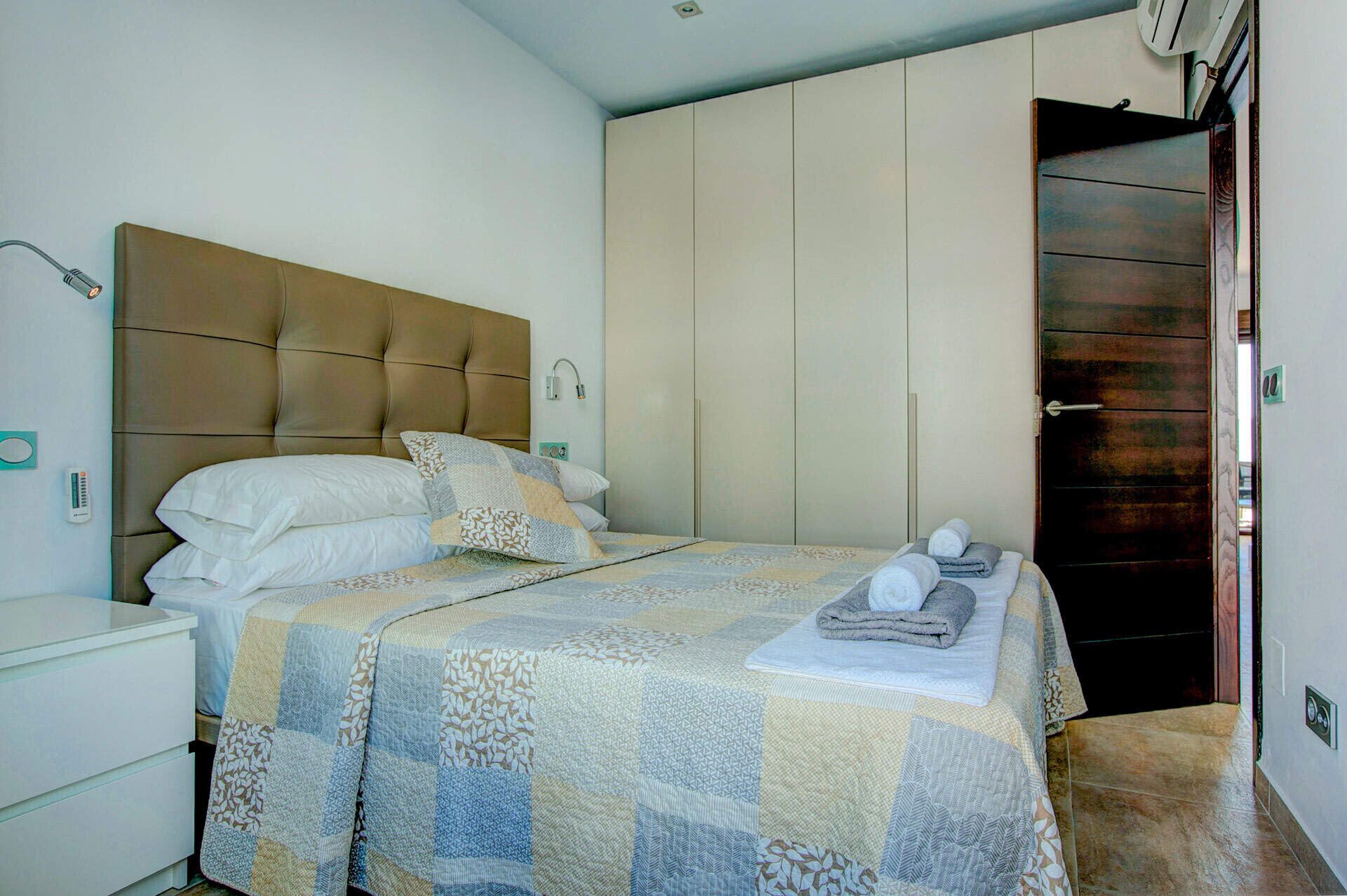 Une chambre à coucher avec un lit, une table de chevet, une armoire et une porte.